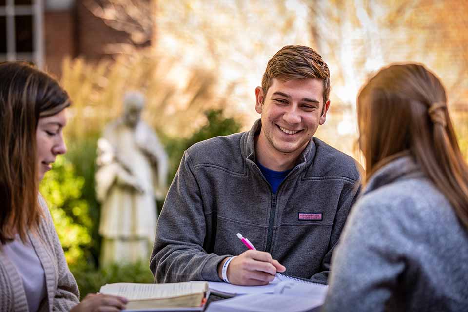 SLU student Male student with pen at table