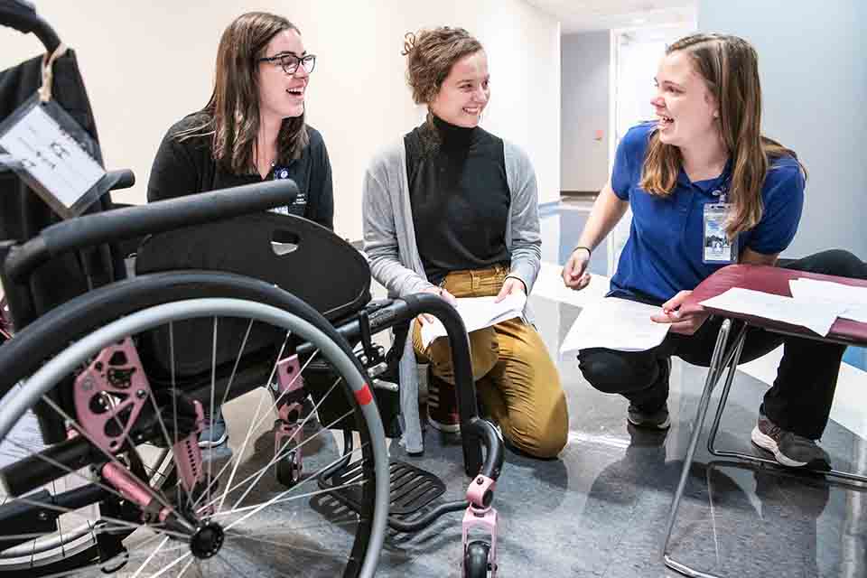 Students in PT class Students in PT class gathered around a wheelchair