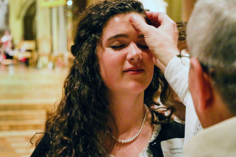 A Mass participant receives ashes on her forehead from a priest.