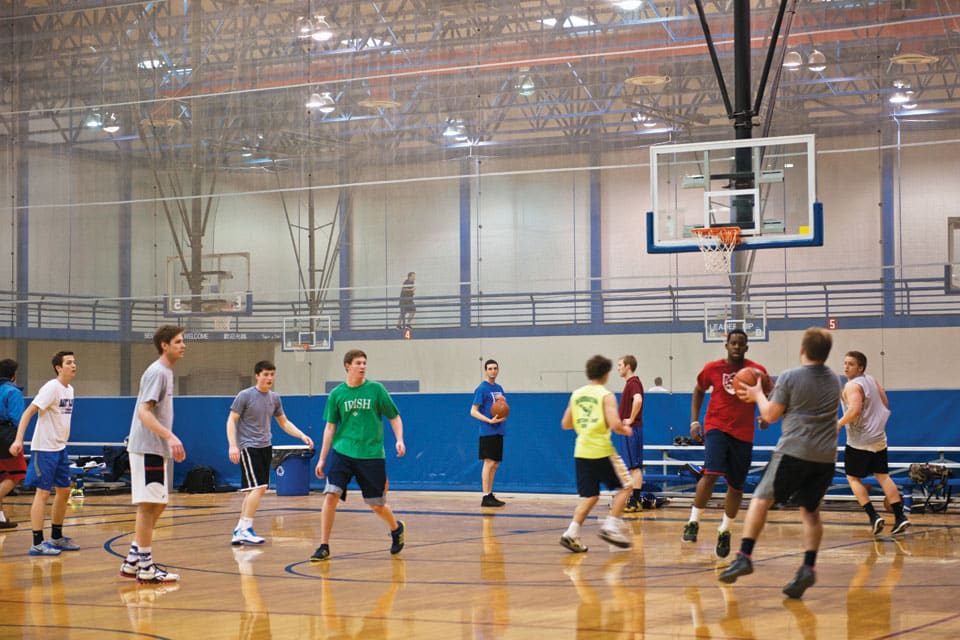 Students play basketball in a gymnasium.