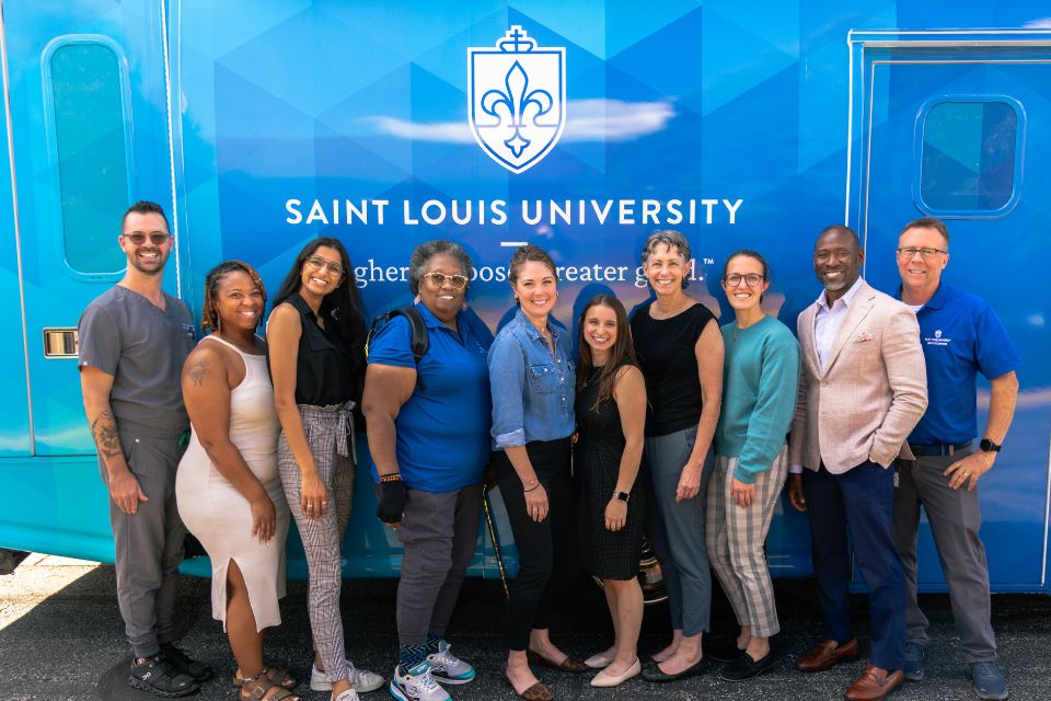 Group photo of partners across SLU that collaborated to created the mobile health clinic standing in front of the van.