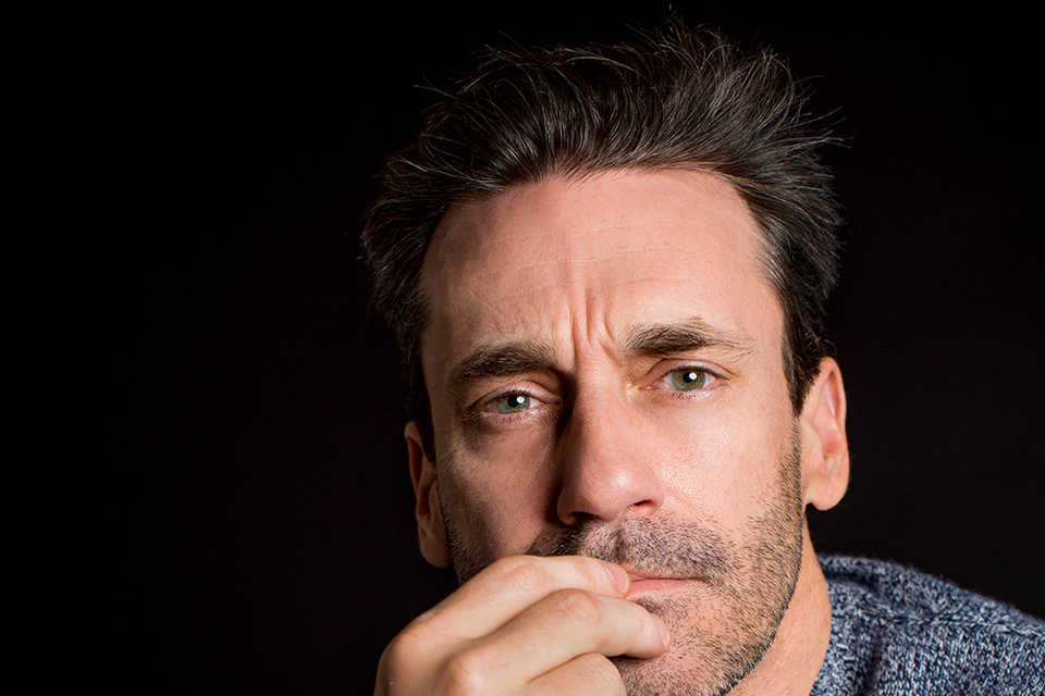 Jon Hamm stares intently into the camera against a black background.