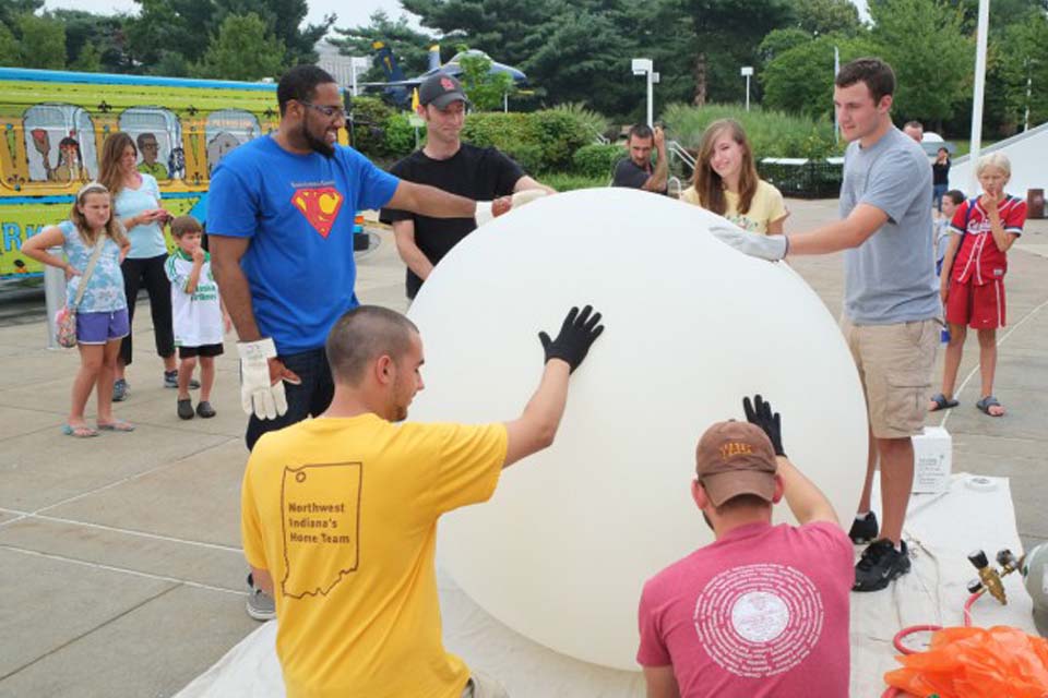 People crowded around a weather balloon that is ready to launch