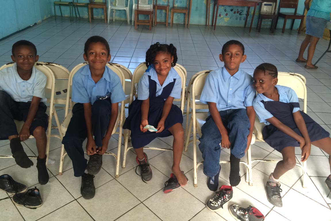 Five Belizean children wait in parish center.