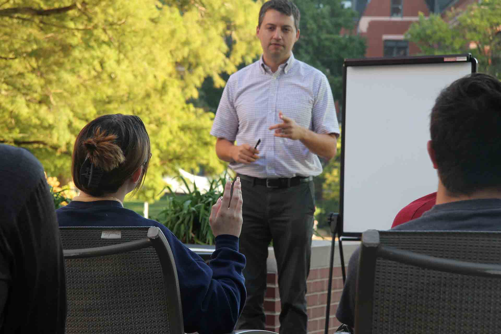 A SLU professor addresses student questions during an outdoor class session.