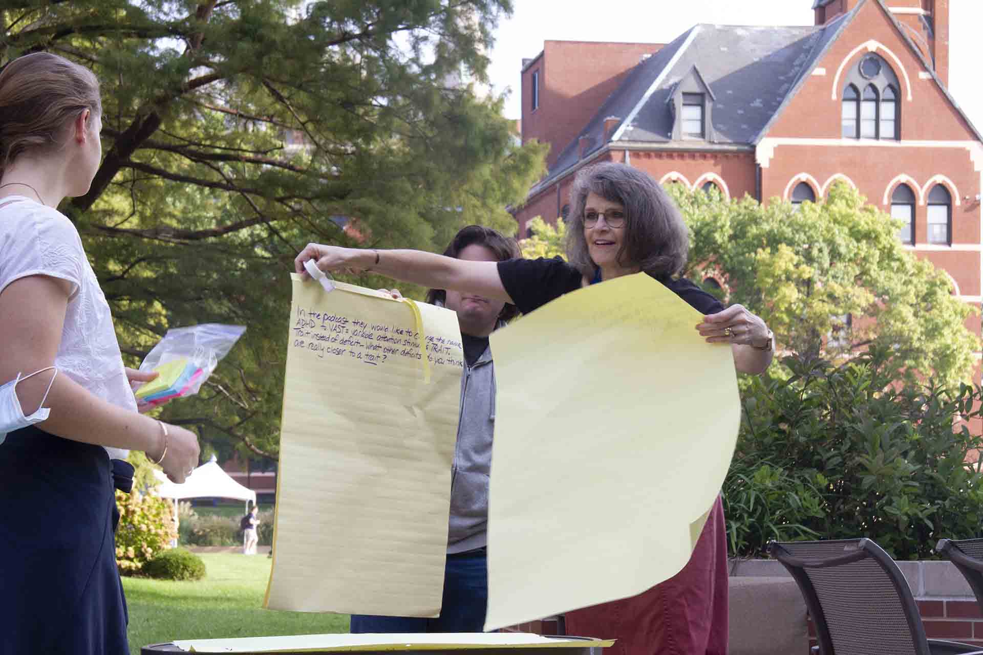 Students hold up a display during an outdoor class discussion.