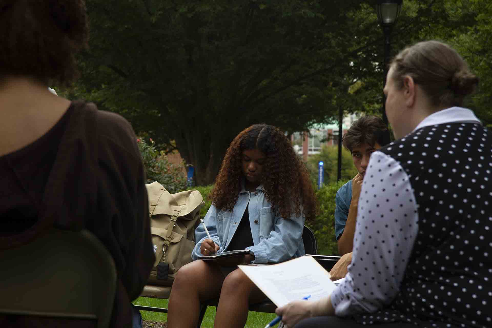 Students take notes during an outdoor class session.