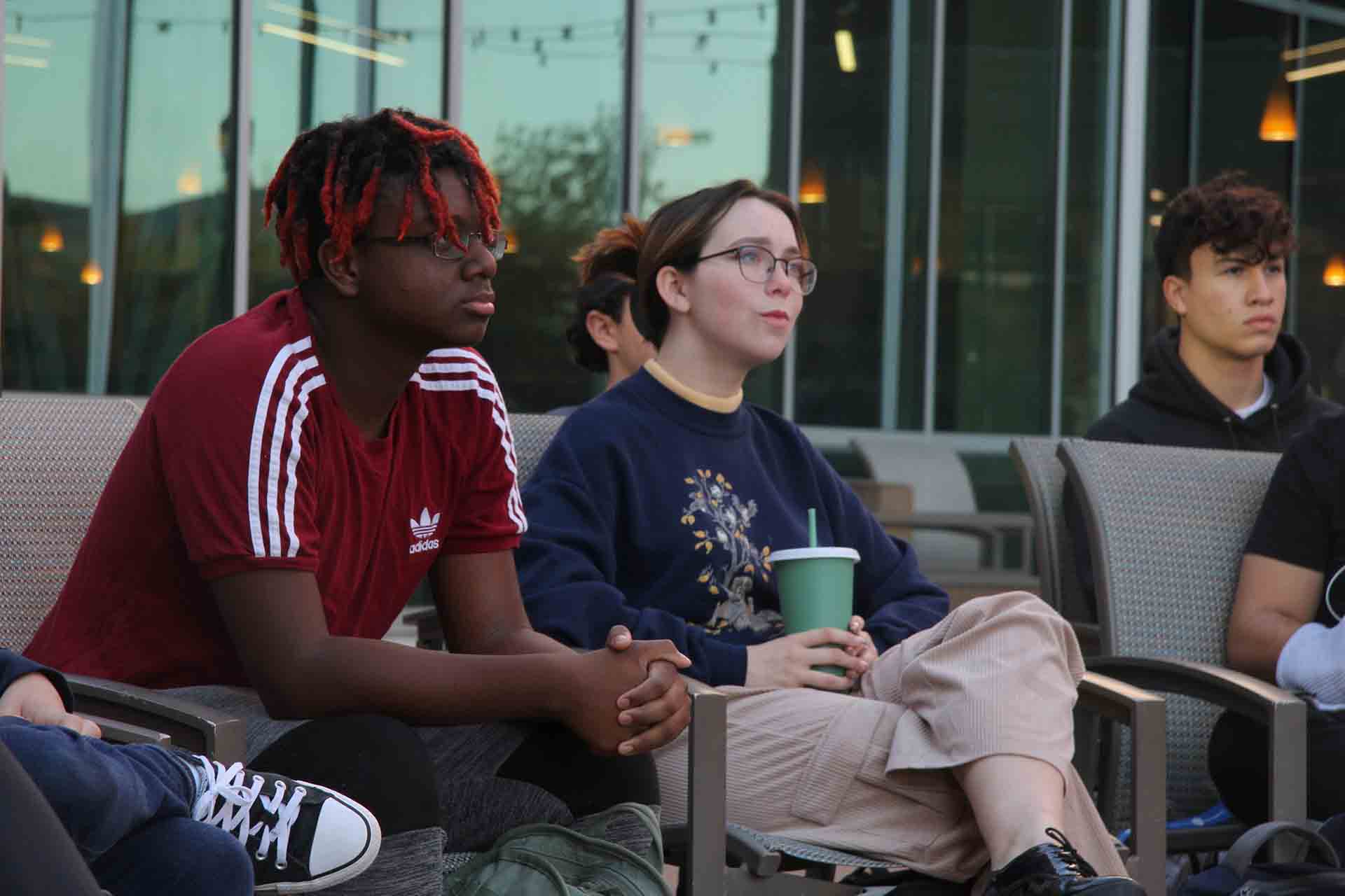 Students sit with attention during an outdoor class session.