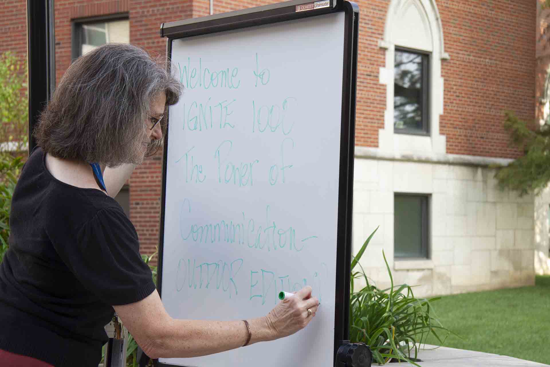 A SLU professor writes notes during an outdoor class session.
