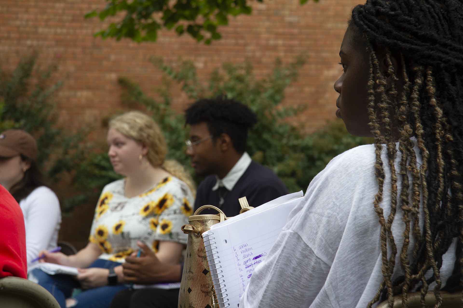 Students sit outdoors during a class discussion.