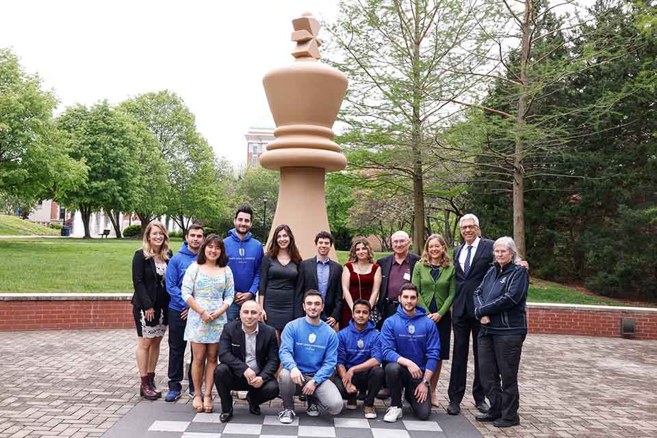Members of the SLU chess team take a picture with Rex and Jeanne Sinquefield, and University President Fred P. Pestello, Ph.D., before the Chess Celebration and dedication of the Sinquefield Chess Commons on May 3, 2022. Photo by Sarah Conroy.  
