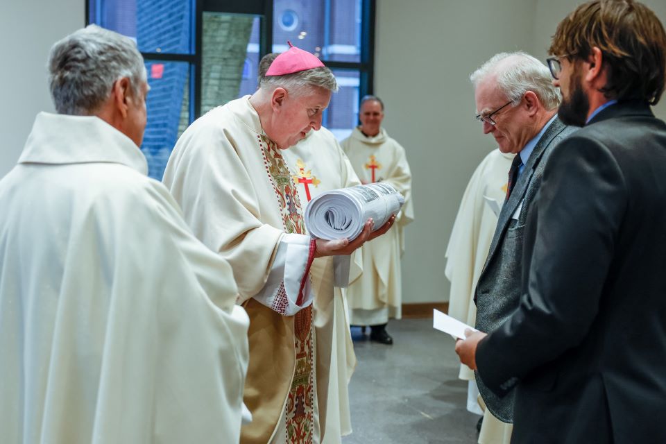 Archbishop. Mitchell T. Rozanski receives the blueprints during the consecration Mass of the Jesuit Center Chapel on October 25, 2022. Photo by Sarah Conroy. 