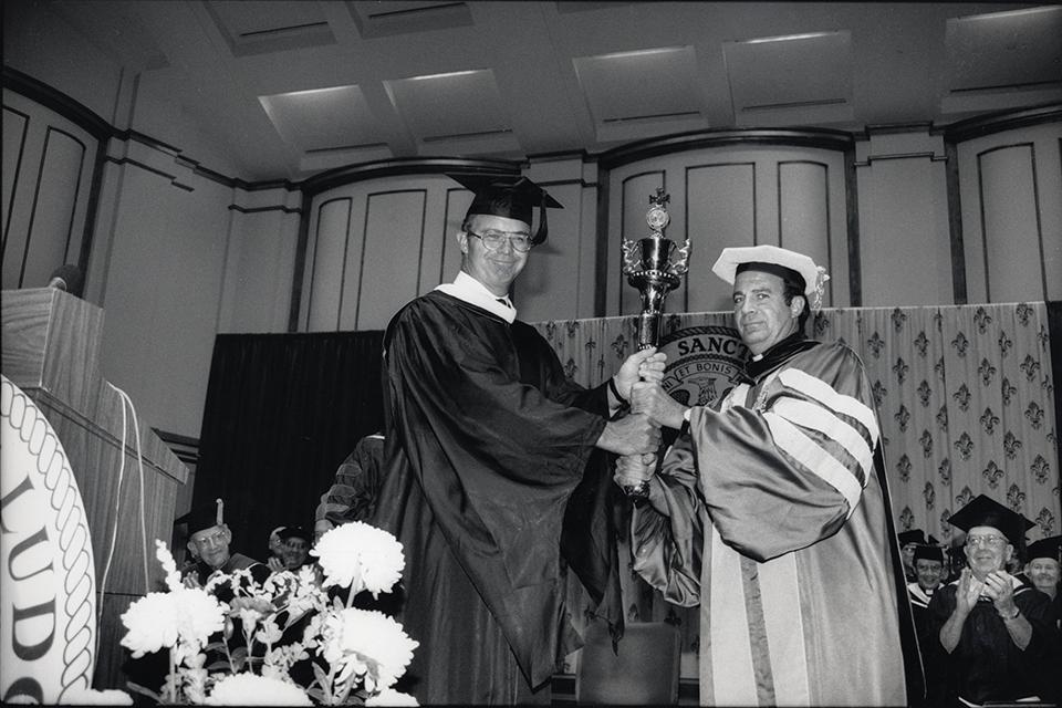 Father Biondi receiving the University Mace from board of Trustees Chairman Bucky Bush at his inauguration as Saint Louis University's 31st president.