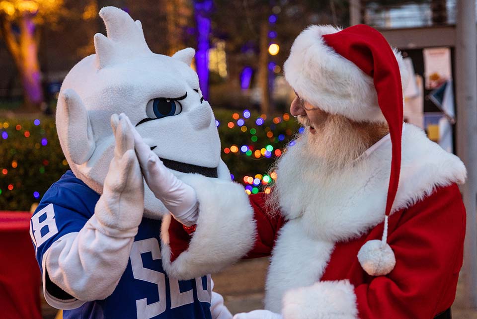 Santa Claus and the Billiken high five during Christmas on the Quad on Saturday, Dec. 3, 2022. Photo by Sarah Conroy. 