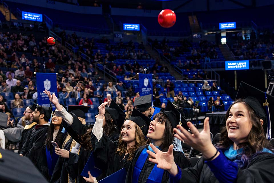 Graduates from the School of Education throw plastic apples during the 2022 Midyear Commencement ceremony at Chaifetz Arena on Saturday, Dec. 17, 2022. Photo by Sarah Conroy.