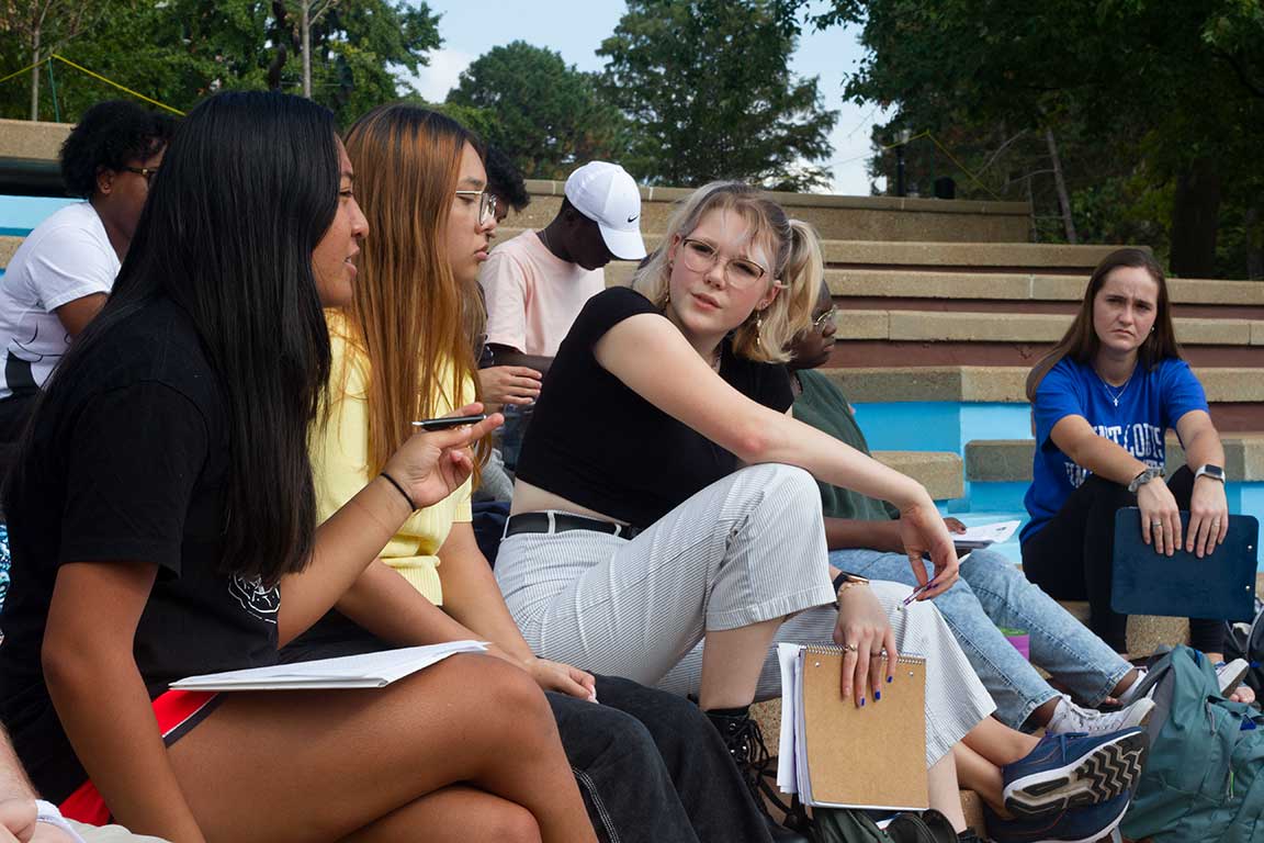 Slide 2: A group of students listening on the clockt ower stairs