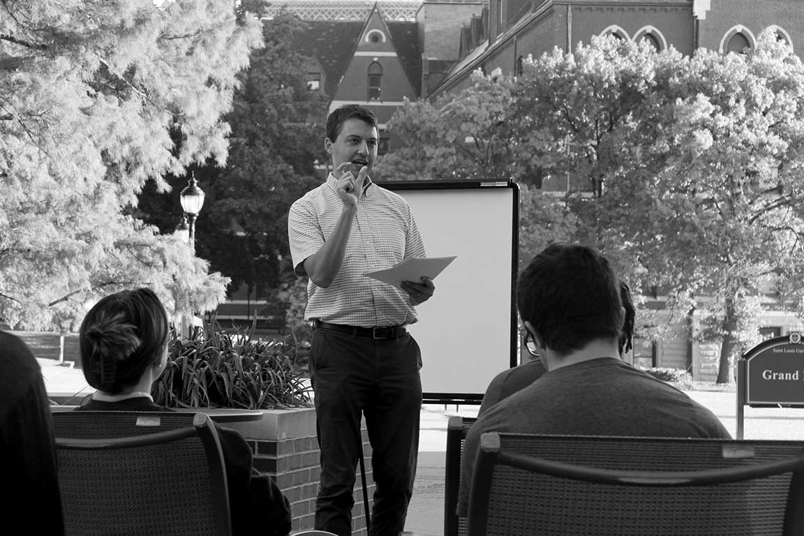 Slide 3: Crowd is addressed Dr. Daniel Smith, Associate Professor of Theological Studies, College of Arts and Sciences