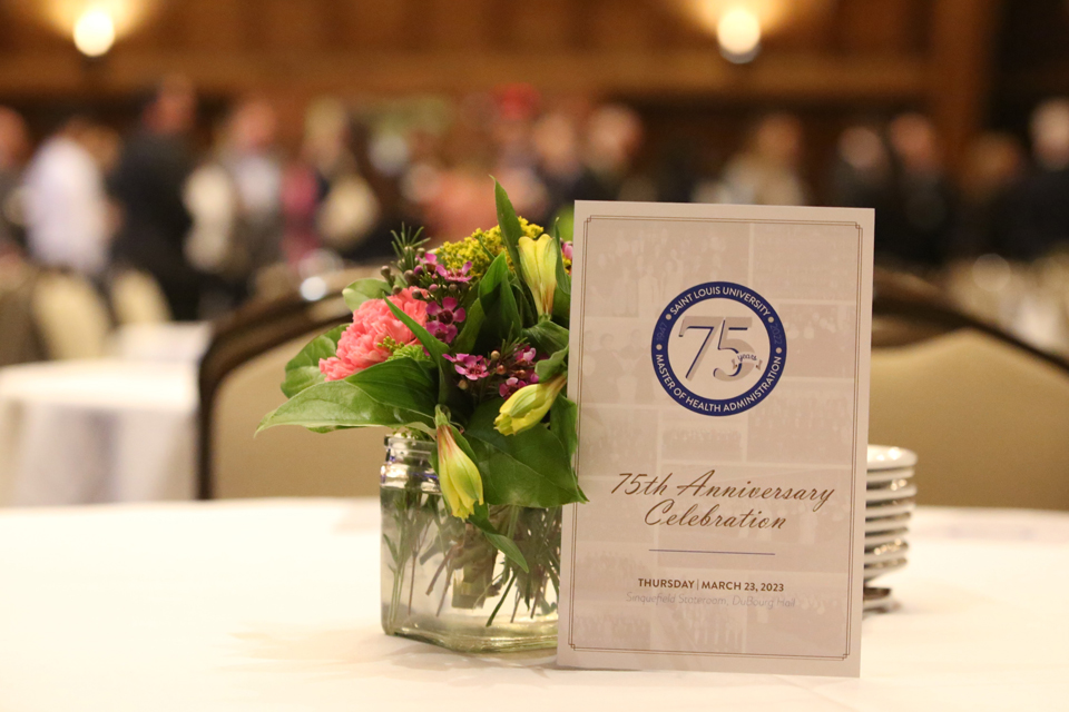 The event program sits on a centerpiece of flowers on a table.