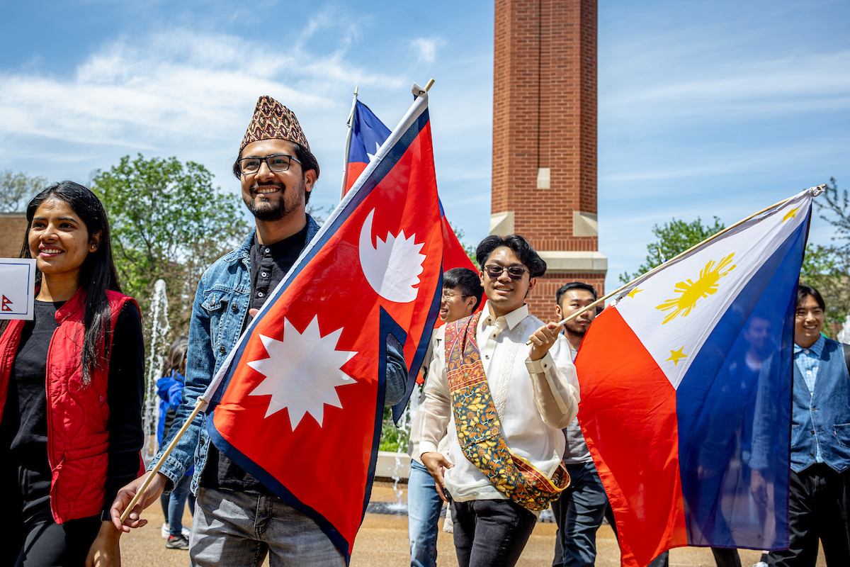 Slide 3: Students carry the flags representing Nepal and the Phillipines.