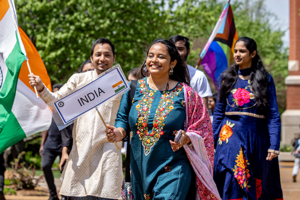 Slide 2: Students representing India walk in traditional dress.