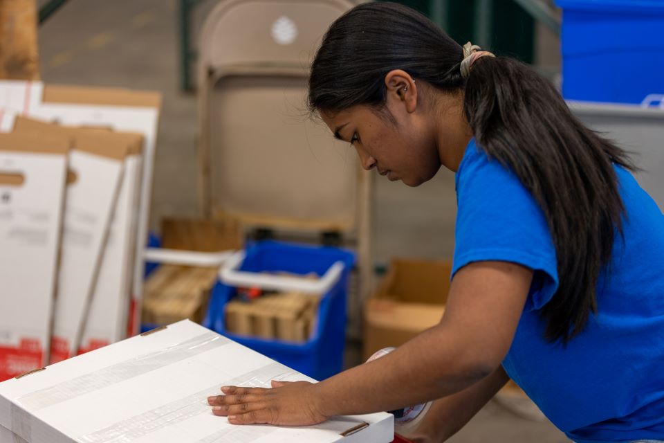 Subah Shovik, vice president of the International Business Club, tapes down a box. Photo by David Malone. 