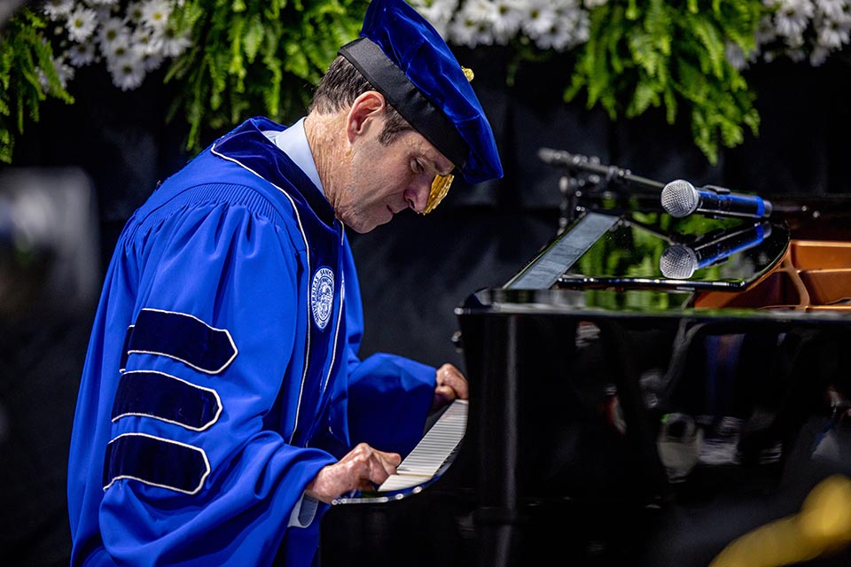 Commencement speaker John O'Leary plays "The Scientist" by Coldplay during the 2023 May Commencement at Chaifetz Arena on May 20, 2023.