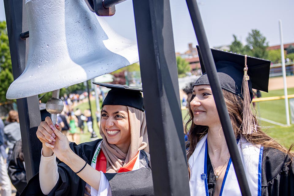 Graduates ring the bell outside Chaifetz Arena following the Spring 2023 Commencement Ceremony. Photo by Sarah Conroy. 
