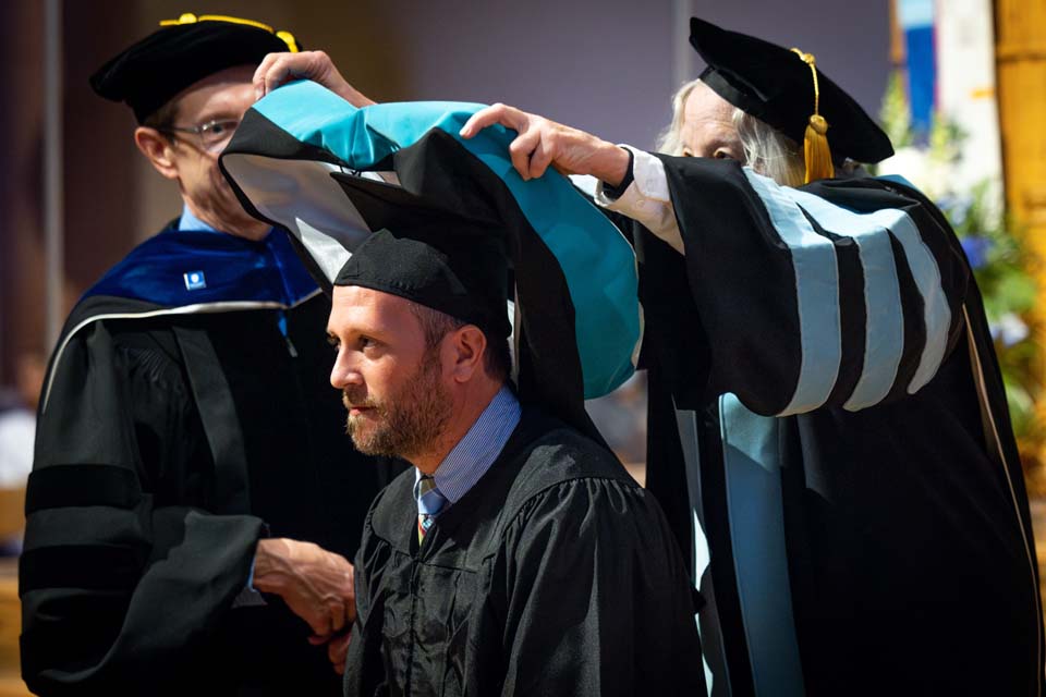 A School of Education graduate is hooded during the precommencement ceremony on May 18, 2023. Photo by Sarah Conroy.