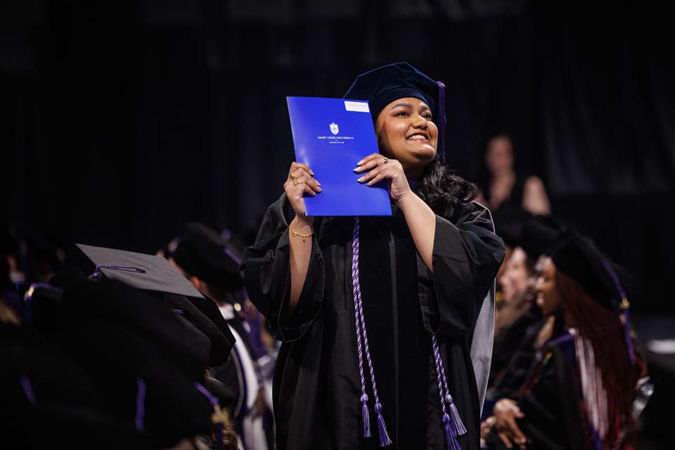 A School of Law graduate holds up her diploma after precommencement at Chaifetz Arena on May 18, 2023. Photo by Sarah Conroy.