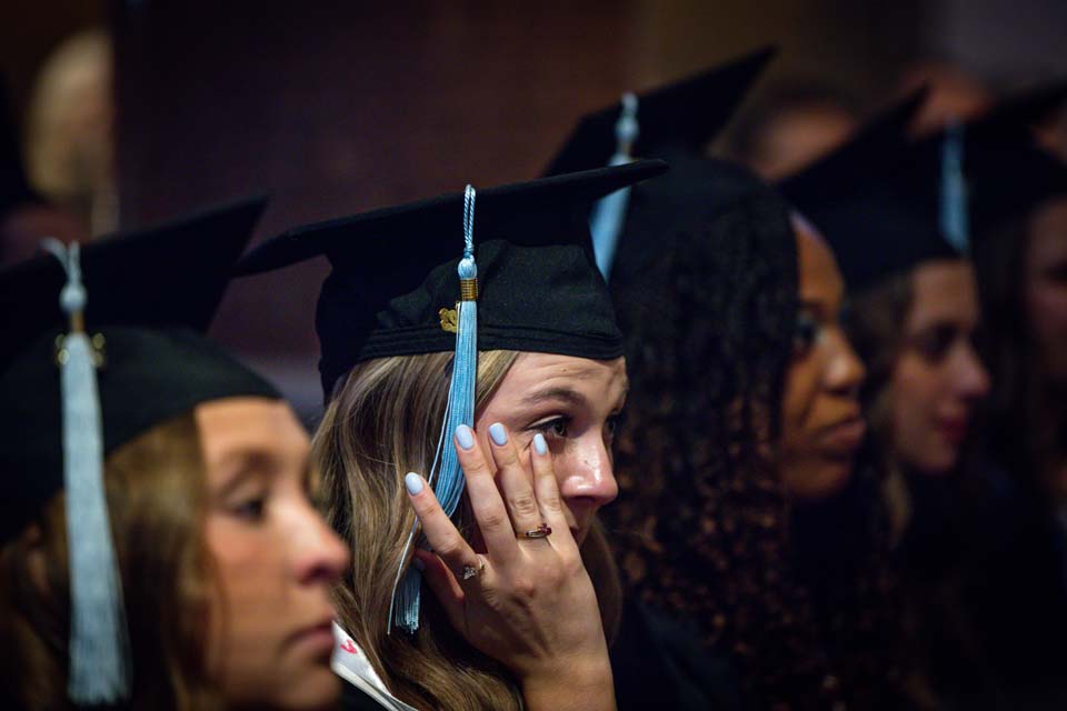 A School of Education graduate wipes away a tear during the precommencement ceremony on May 18, 2023. Photo by Sarah Conroy.