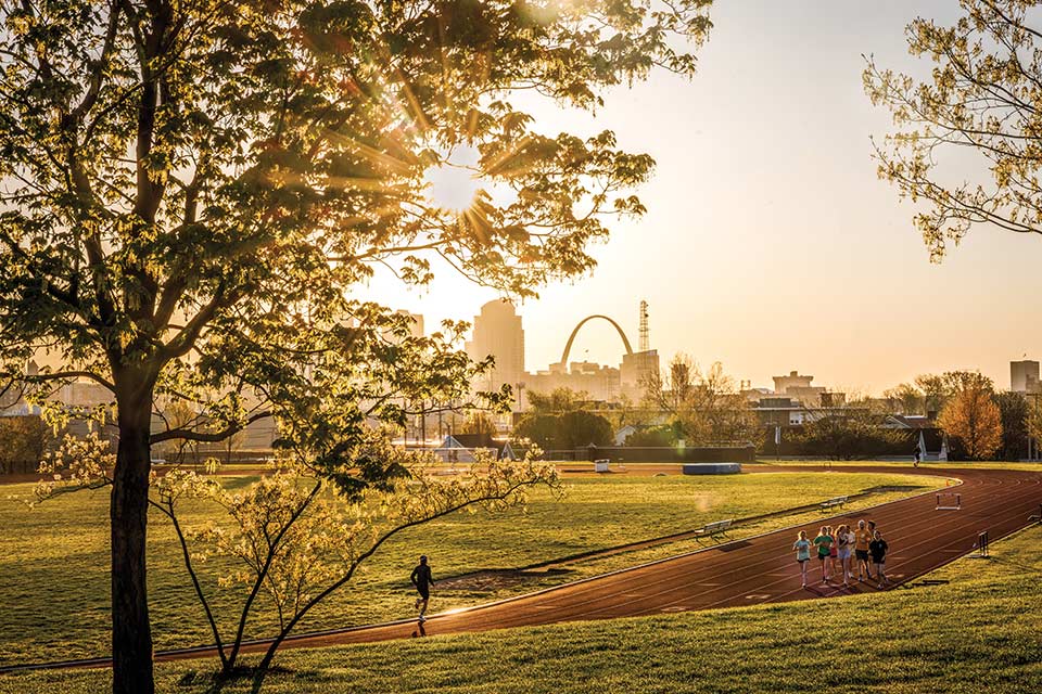 6:58 a.m. - The sun rises over early-morning runners at the Medical Center Stadium. - Photo by Sarah Conroy