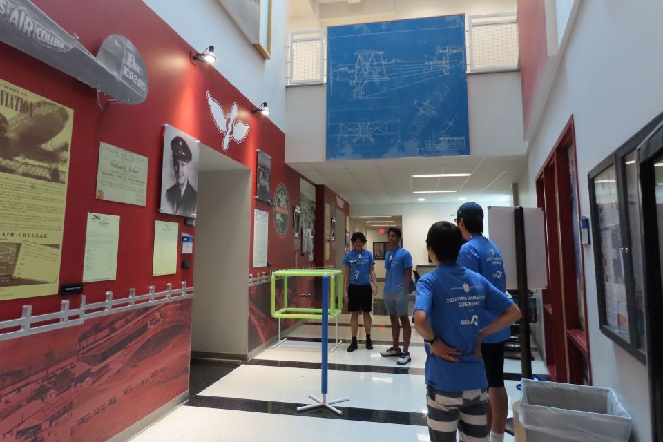 STEM Camp students Isaac Gutierrez, Aadit Mehta, Charles Ma and Sohji Matsuda fly drones through the halls of McDonnell Douglas Hall. Photo by Maggie Rotermund.