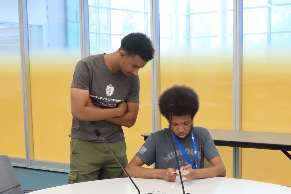STEM camp counselor Abdelrahman Ibrahim looks over the shoulder of Sebastian Nolen during during a CHROME lab activity. Photo by Maggie Rotermund.