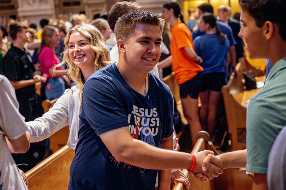 Students share the sign of peace during the Mass of the Holy Spirit in St. Francis Xavier College Church on Thursday, Aug. 24. Photo by Sarah Conroy. 