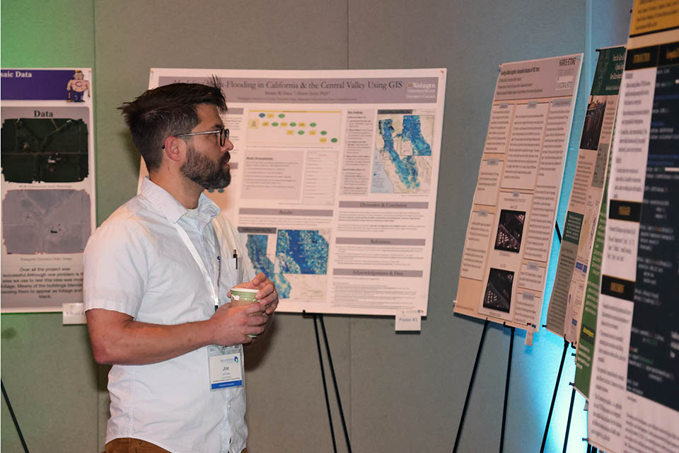 An attendee at the 2023 Geo-Resolution Conference checks out posters on display. Photo by Joe Barker. 