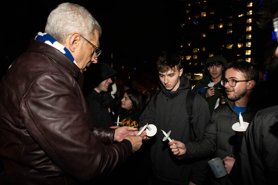 SLU President Fred P. Pestello, Ph.D., lights candles with students at Christmas on the Quad on Saturday, Dec. 9. Photo by Luke Yamnitz.