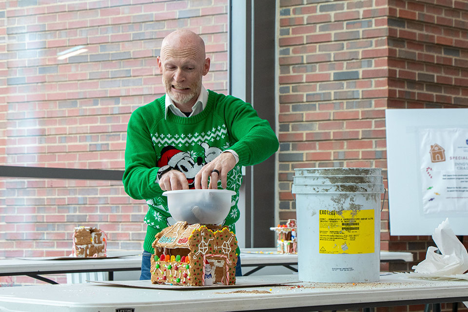Scott Sell, Ph.D., professor of biomedical engineering, adds weight to a gingerbread house built for SSE's December Innovation Challenge. Photo by Tyler Merkle. 