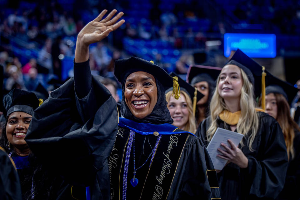 A graduate waves to loved ones in the crowd during the Midyear Commencement on Dec. 16, 2023. Photo by Sarah Conroy.