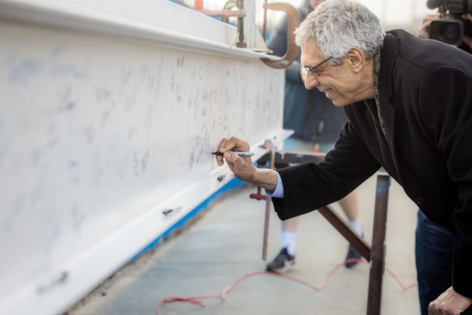 Saint Louis University President Fred P. Pestello, Ph.D., signs a construction beam during the topping-out ceremony for SLU’s O’Loughlin Family Champions Center on Jan. 23, 2023. The center opened in October 2023. Photo courtesy of Saint Louis University. 