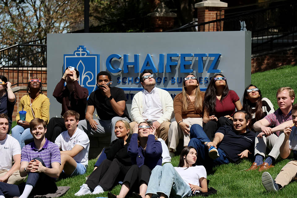 A crowd of watchers camped outside the Chaifetz School of Business at Saint Louis University to catch a glimpse of the solar eclipse on Monday, April 5. Photo by Joe Barker. 
