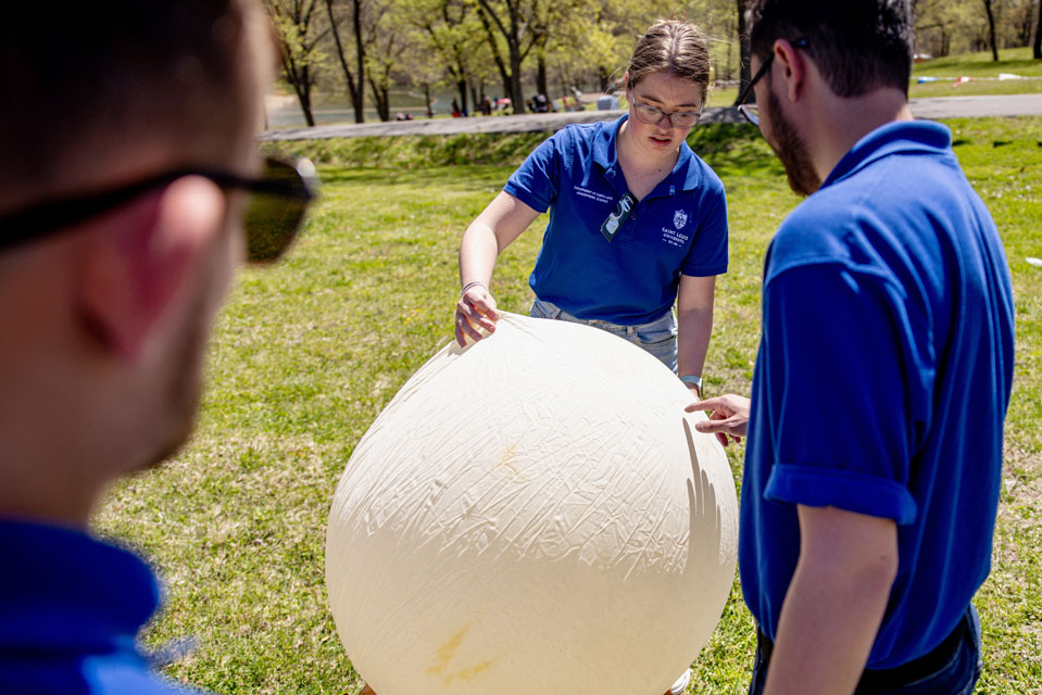 Maggie Ideker, center, and Riley Jackson, inflate a weather balloon during the solar eclipse at Trail of Tears State Park on April 8, 2024. Photo by Sarah Conroy. 
