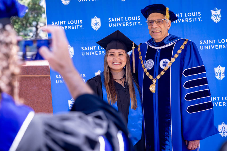 President Fred P. Pestello, Ph.D., takes photos with graduates after Commencement on May 18, 2024. Photo by Sarah Conroy. 