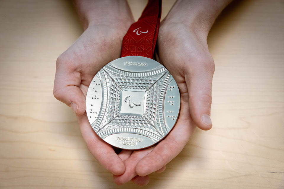 Sarah Adam, OTD, assistant professor of occupational science and occupational therapy, shows her Paralympic silver medal on her first day back to campus on Monday, Sept. 9, 2024. Adam made history as the first woman to represent the US Wheelchair Rugby team in the Paralympics and won a silver medal. Photo by Sarah Conroy.