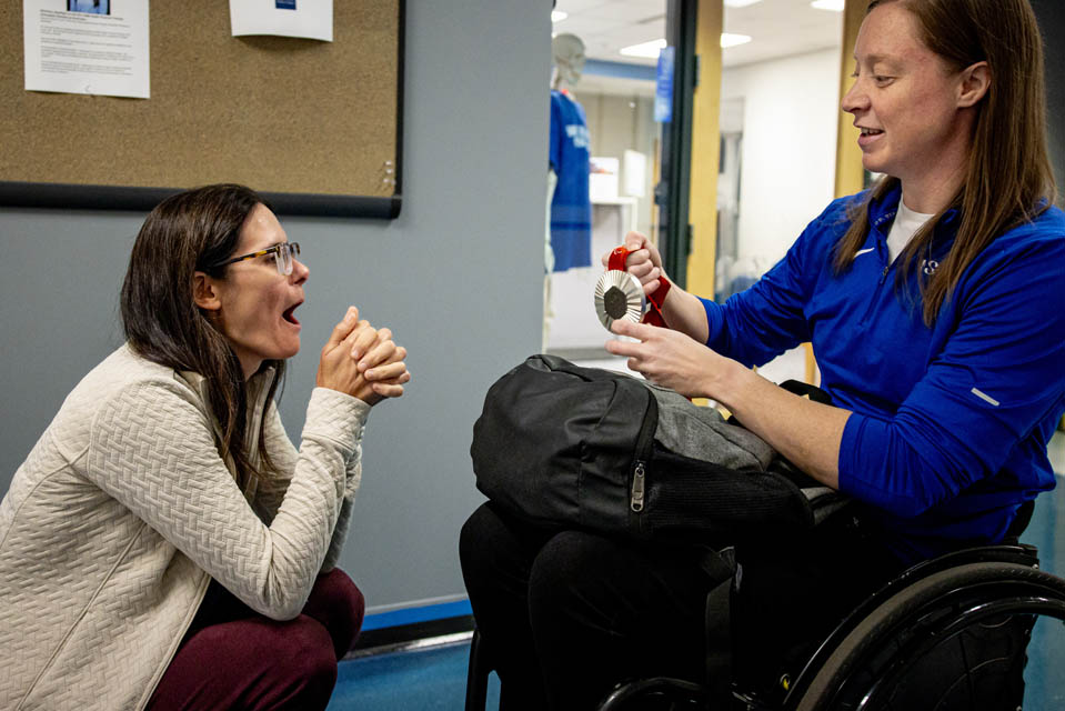 Sarah Adam, OTD, assistant professor of occupational science and occupational therapy, shows her Paralympic silver medal on her first day back to campus on Monday, Sept. 9, 2024. Adam made history as the first woman to represent the US Wheelchair Rugby team in the Paralympics and won a silver medal. Photo by Sarah Conroy.