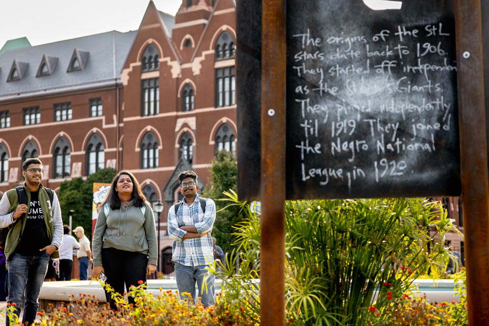 Students view a piece from “The Legacy of Mill Creek,” an art installation by Cbabi Bayoc surrounding the fountain at Grand and Lindell Blvds. The installation honors the vibrant historically Black community that lived in the former Mill Creek Valley neighborhood. Photo by Sarah Conroy. 