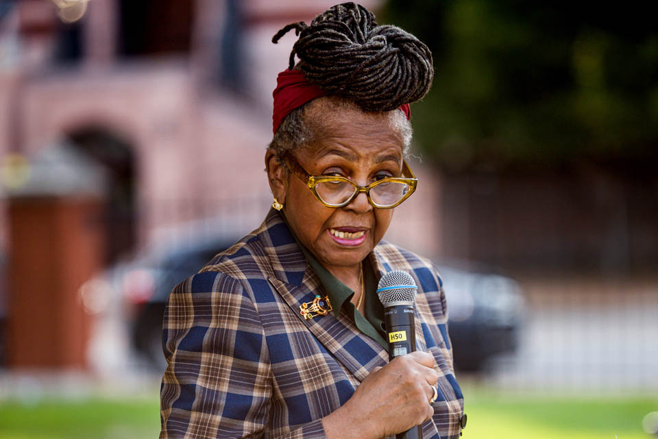 Malaika Horne, Ph.D., a former Mill Creek community member, speaks during the celebration for “The Legacy of Mill Creek,” an art installation by Cbabi Bayoc surrounding the fountain at Grand and Lindell Blvds. The installation honors the vibrant historically Black community that lived in the former Mill Creek Valley neighborhood. Photo by Sarah Conroy. 