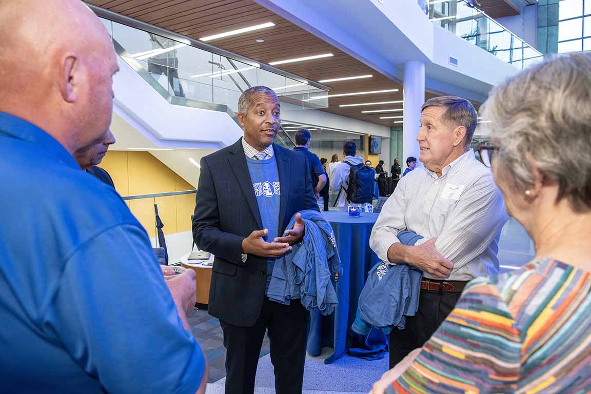 The dean of the School of Science and Engineering talks with attendees at an open house.
