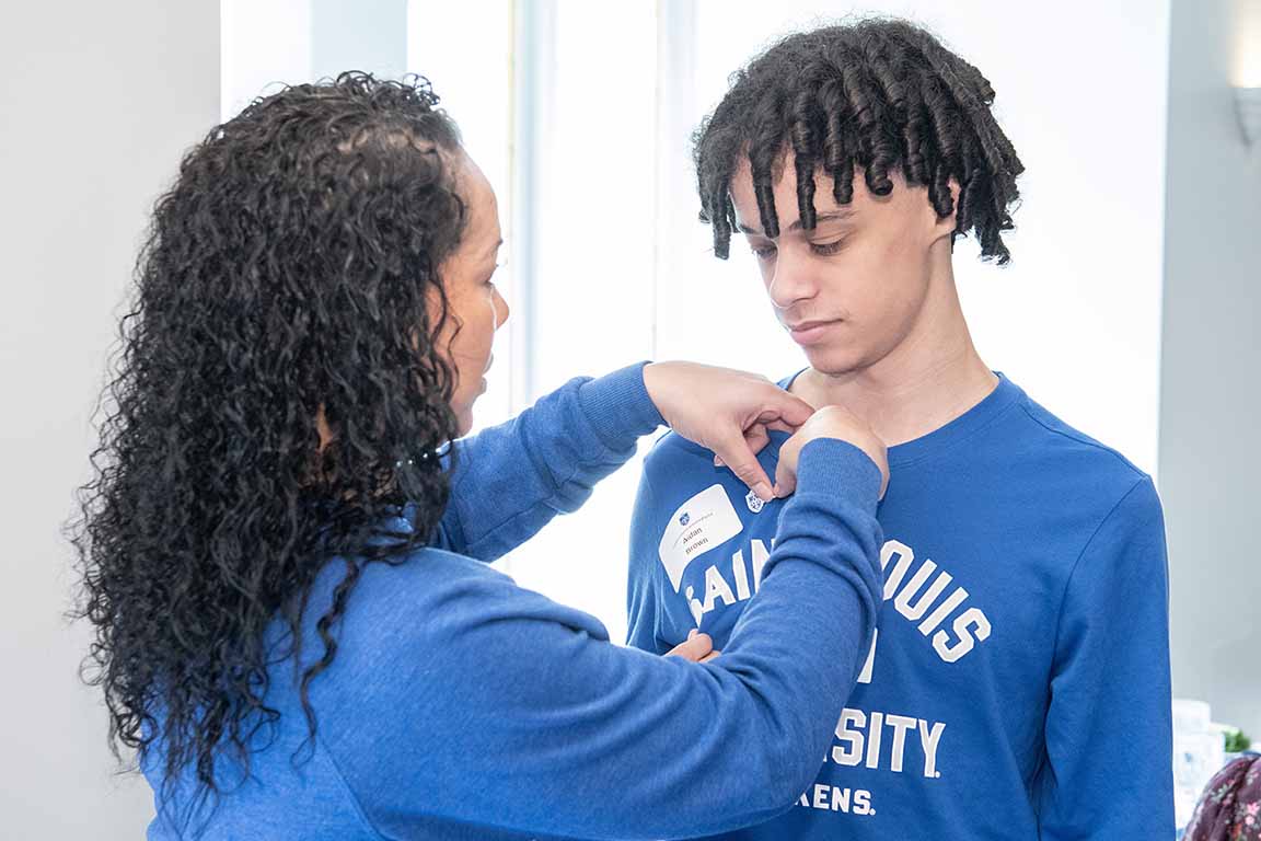 An alumnae pins a Saint Louis University pin on a legacy student at SLU's 2024 Homecoming and Family Weekend Legacy Luncheon. 