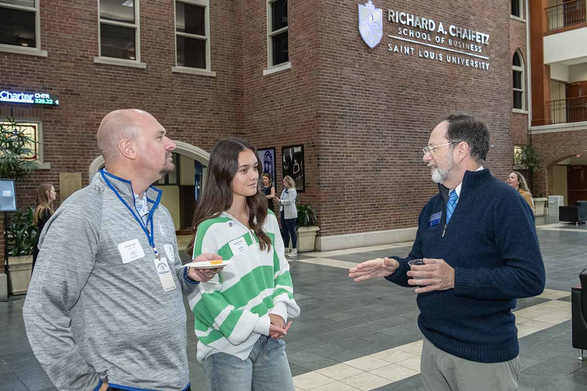 The dean of the Chaifetz School of Business talks to guests at an open house.