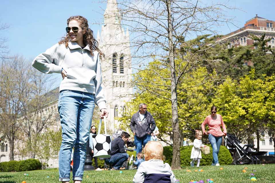 Families help their children find eggs in a field on campus. 